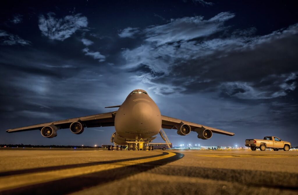 A large cargo plane stationed on the tarmac under the night sky, ready for transport.